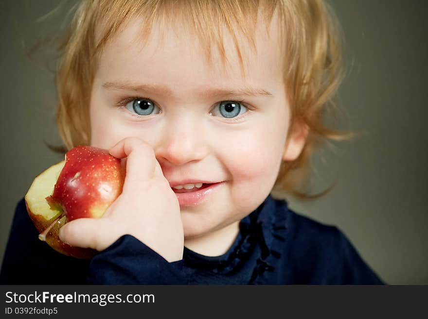 A little beautiful girl eating an apple. A little beautiful girl eating an apple