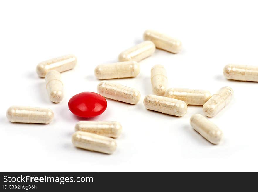 Red capsule and pills on white background