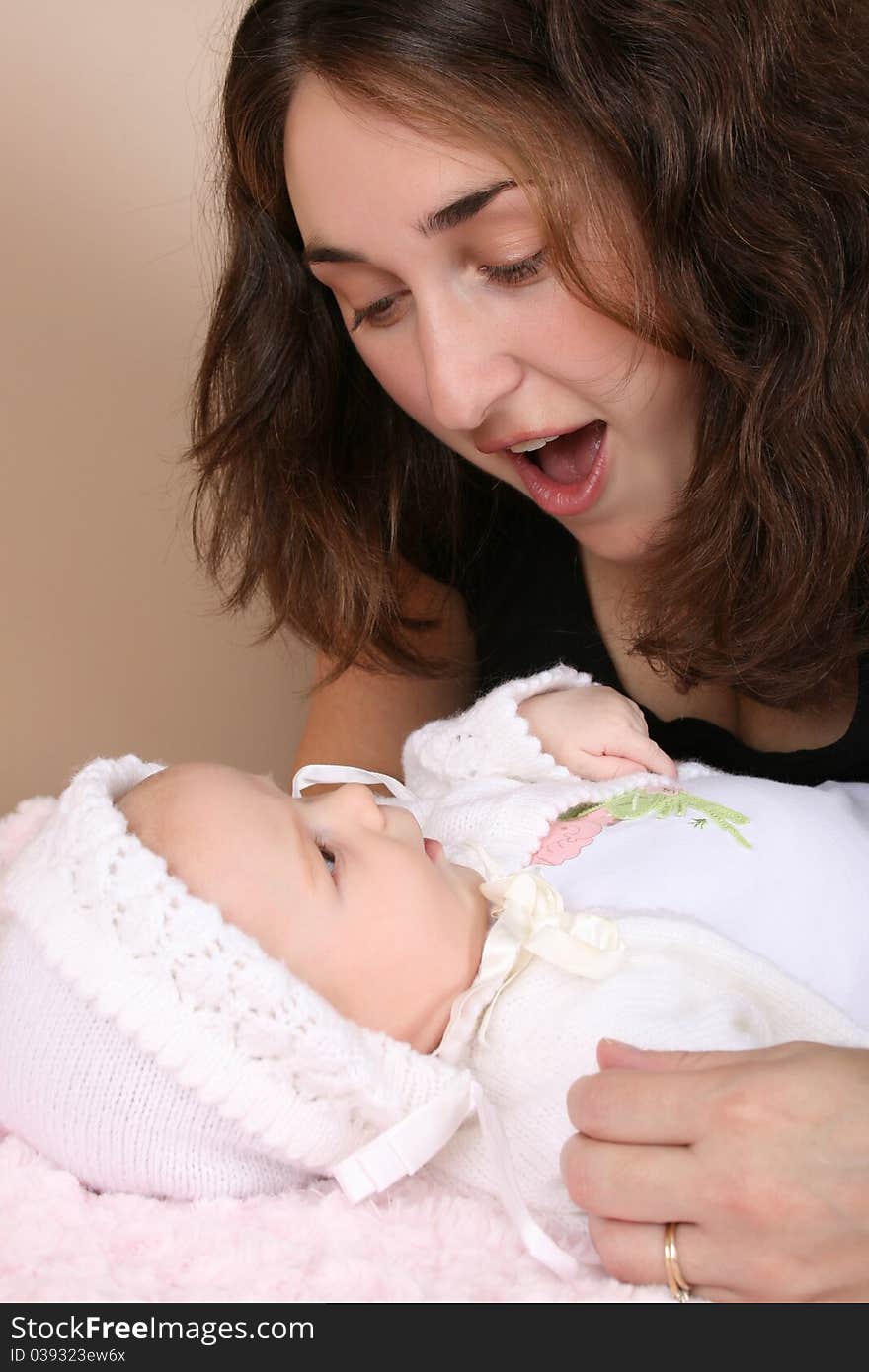 Beautiful brunette mother looking at her two month old baby girl. Beautiful brunette mother looking at her two month old baby girl