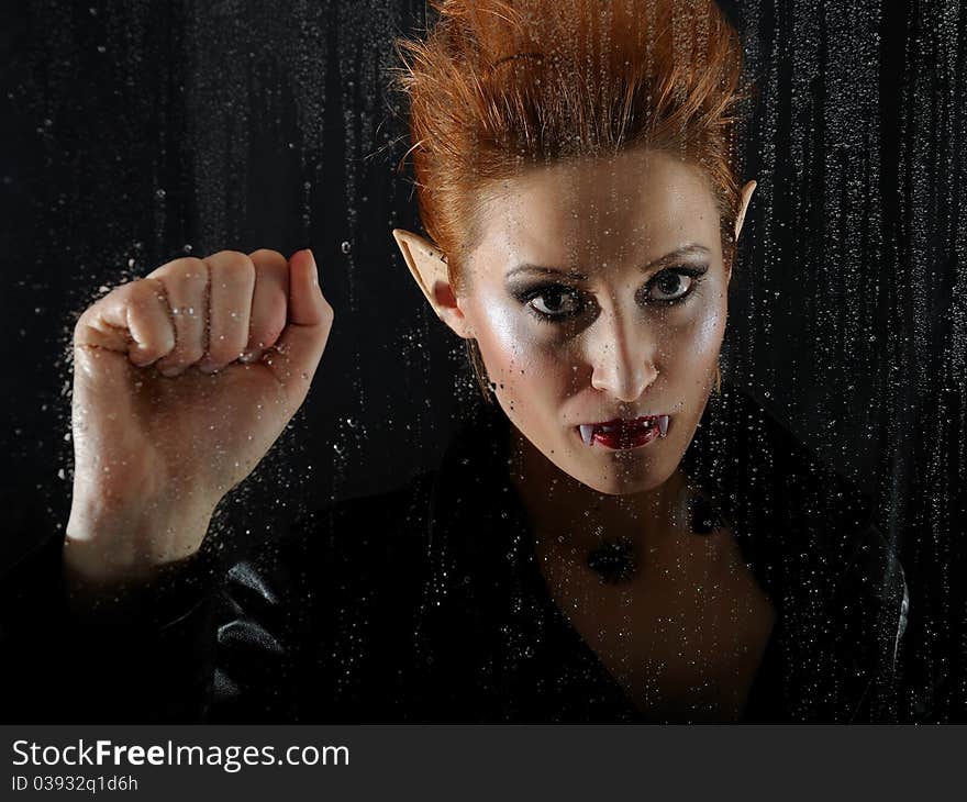 Portrait horrible fashion vampire woman behind rainy window. Portrait horrible fashion vampire woman behind rainy window