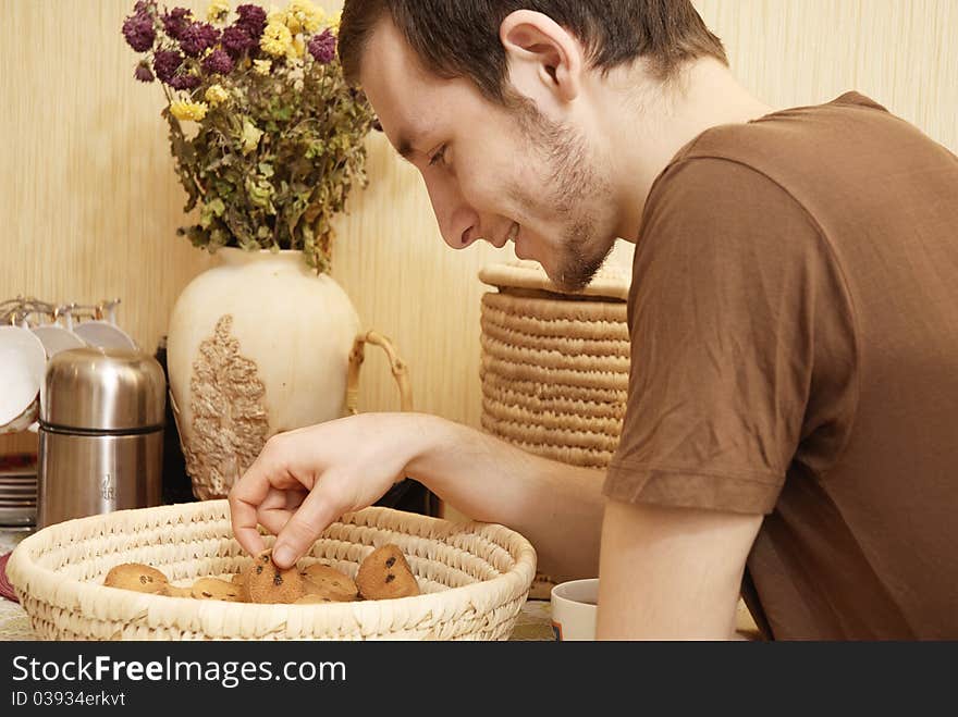 Young guy with tea and rusk in the kitchen