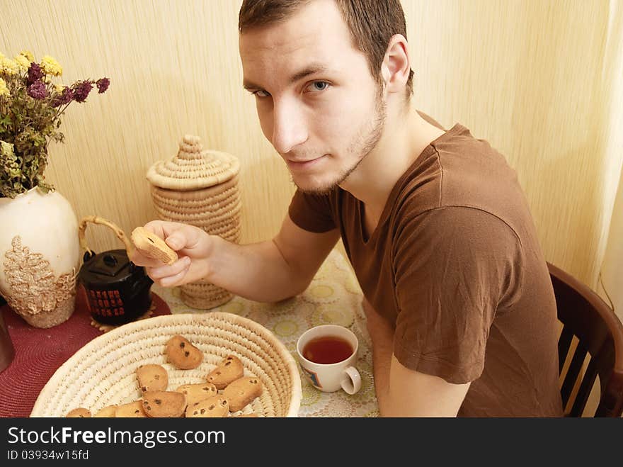 Young guy with tea and rusk in the kitchen