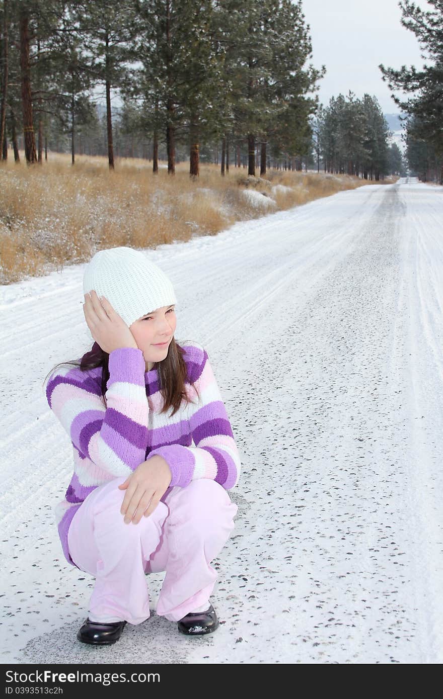 Young girl sitting in the middle of a long isolated road. Young girl sitting in the middle of a long isolated road