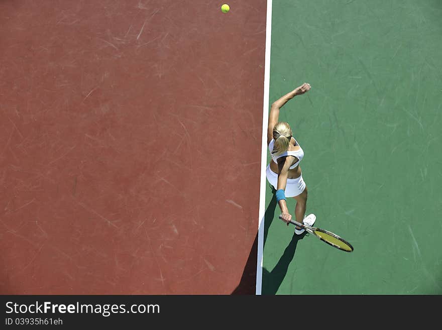 Young fit woman play tennis outdoor on orange tennis field at early morning. Young fit woman play tennis outdoor on orange tennis field at early morning