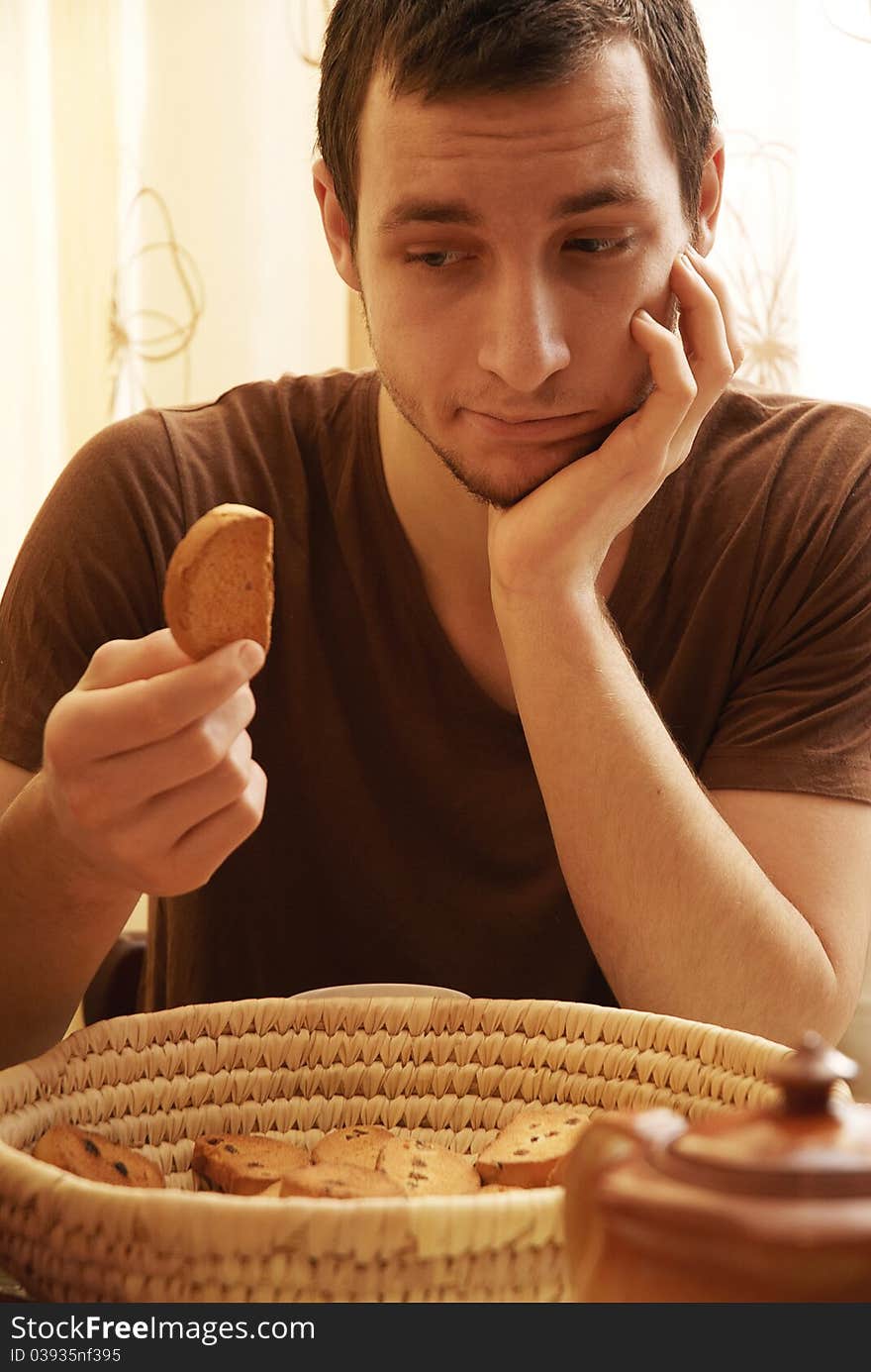 Young guy with tea and rusk in the kitchen