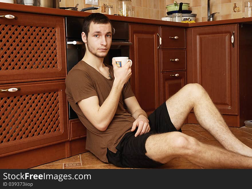 Young Guy With Tea And Rusk In The Kitchen