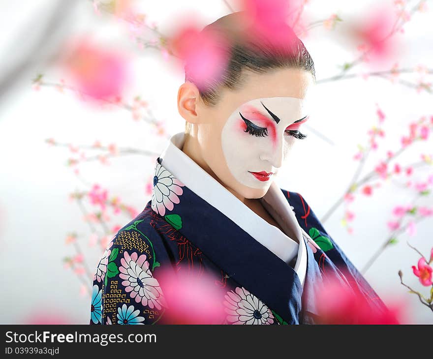 Artistic portrait of japan geisha woman with creative make-up near sakura tree