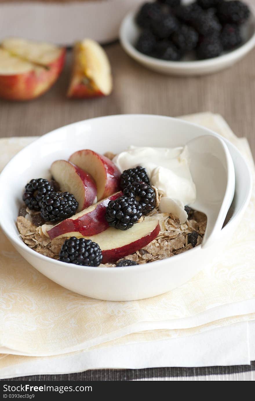 Muesli with fresh apples, blackberries and yogurt in a bowl