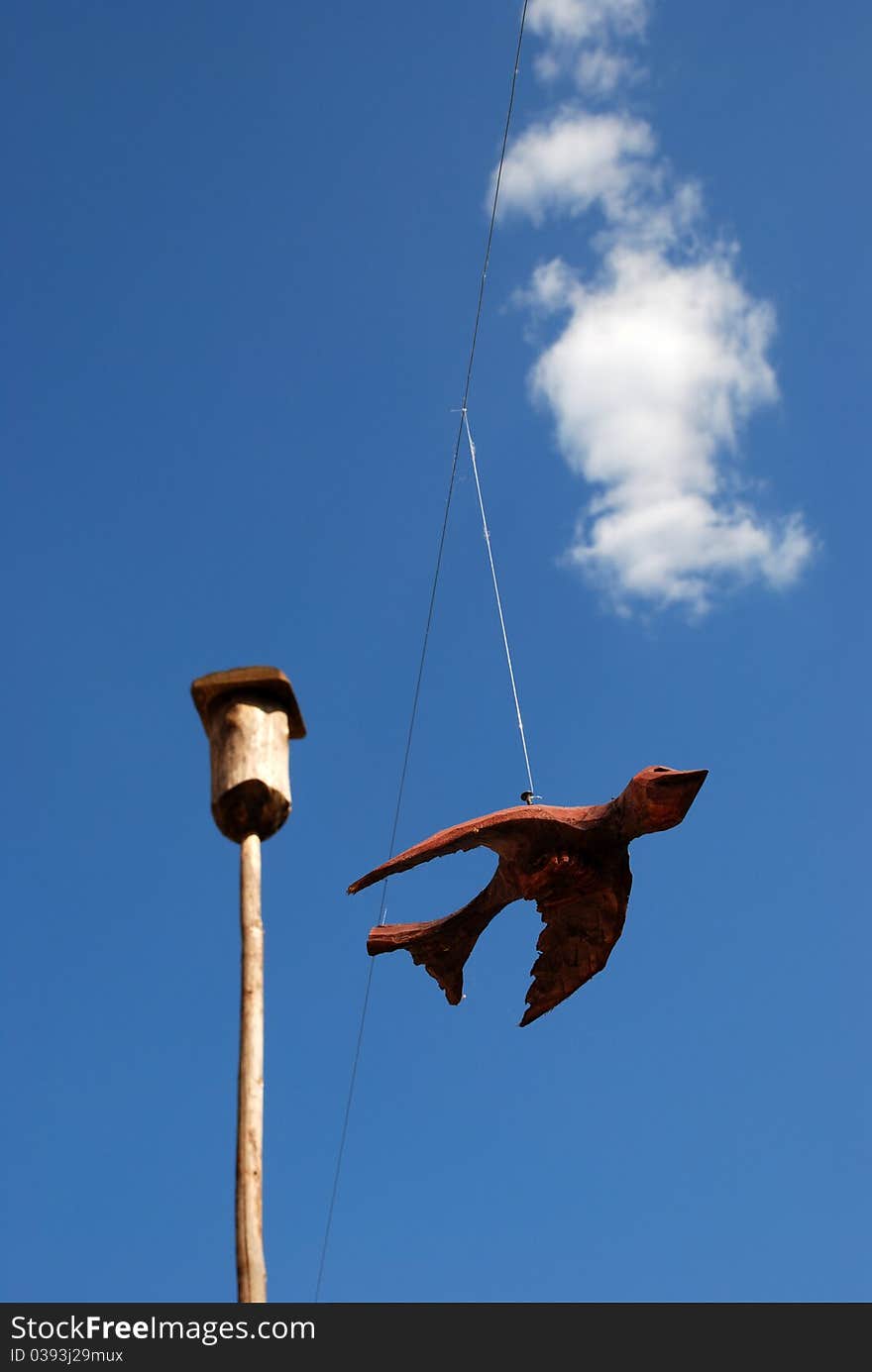 Wooden bird on blue sky near nesting-box