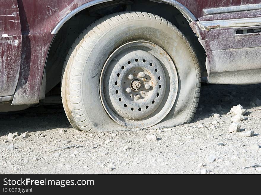 A flat tyre on a red well used car. A flat tyre on a red well used car