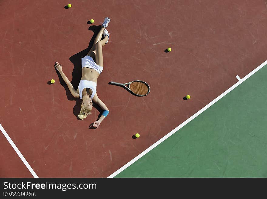 Young fit woman play tennis outdoor on orange tennis field at early morning. Young fit woman play tennis outdoor on orange tennis field at early morning