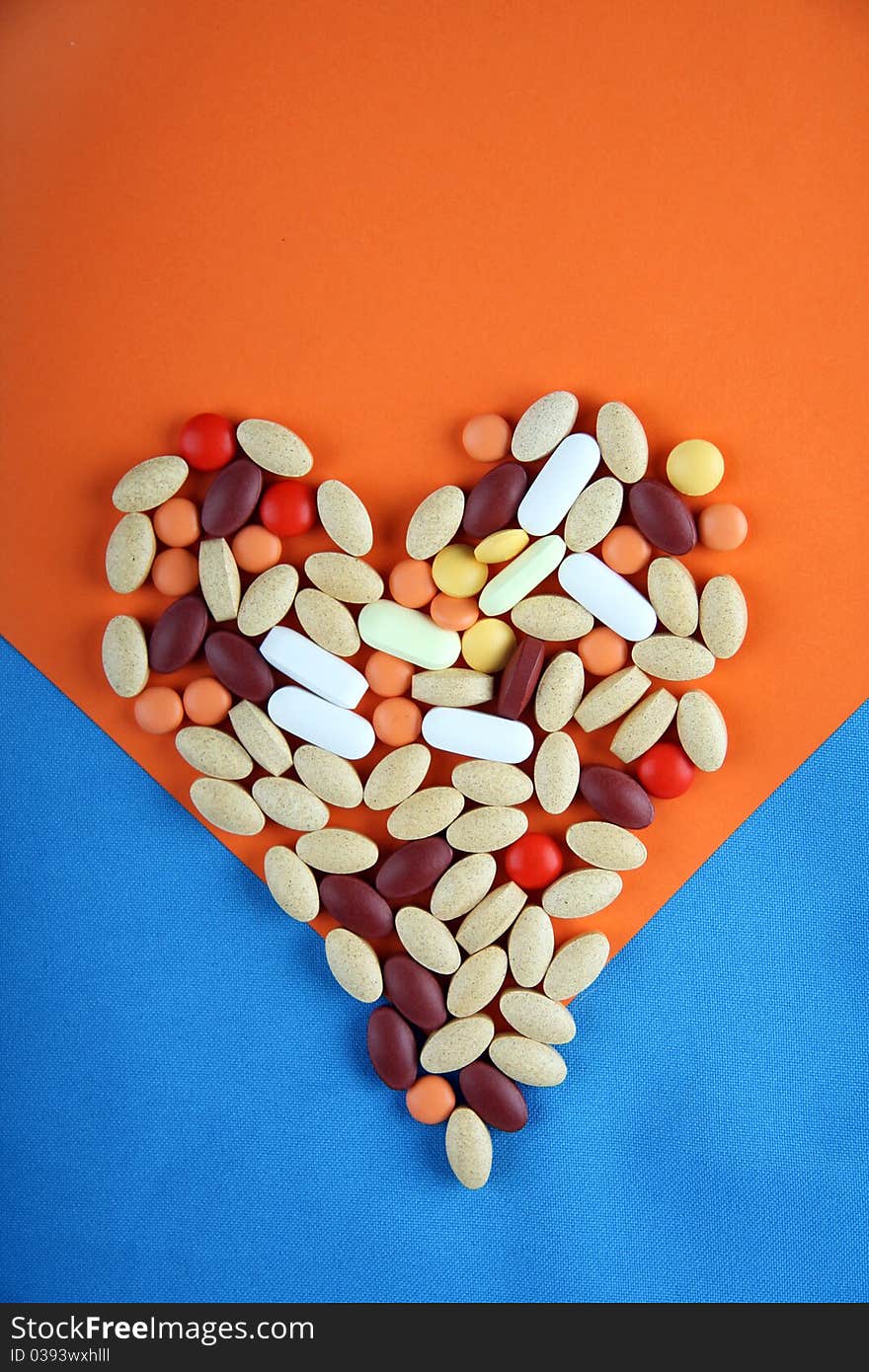 Pills in shape of love heart on orange and blue background. Pills in shape of love heart on orange and blue background