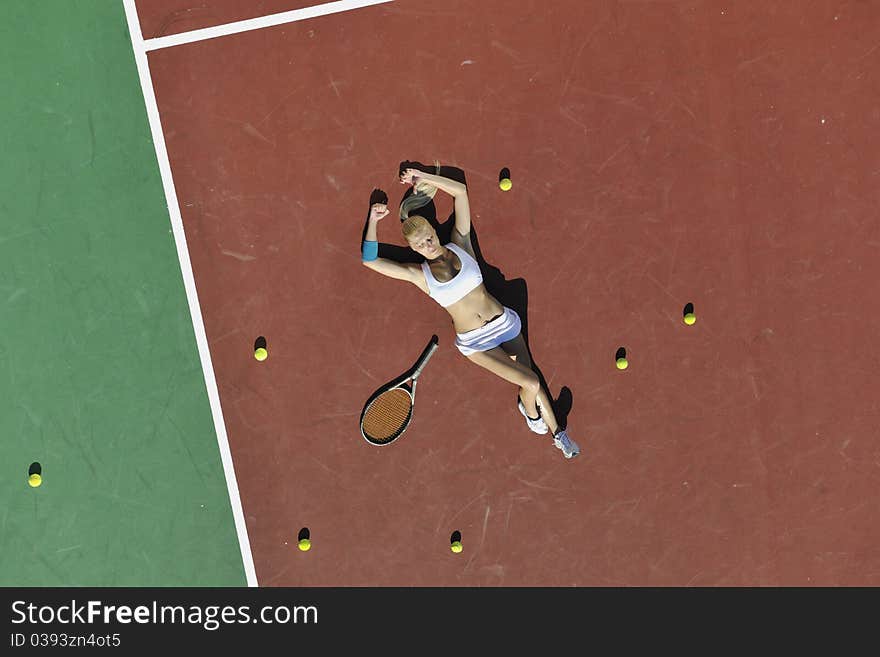 Young fit woman play tennis outdoor on orange tennis field at early morning. Young fit woman play tennis outdoor on orange tennis field at early morning