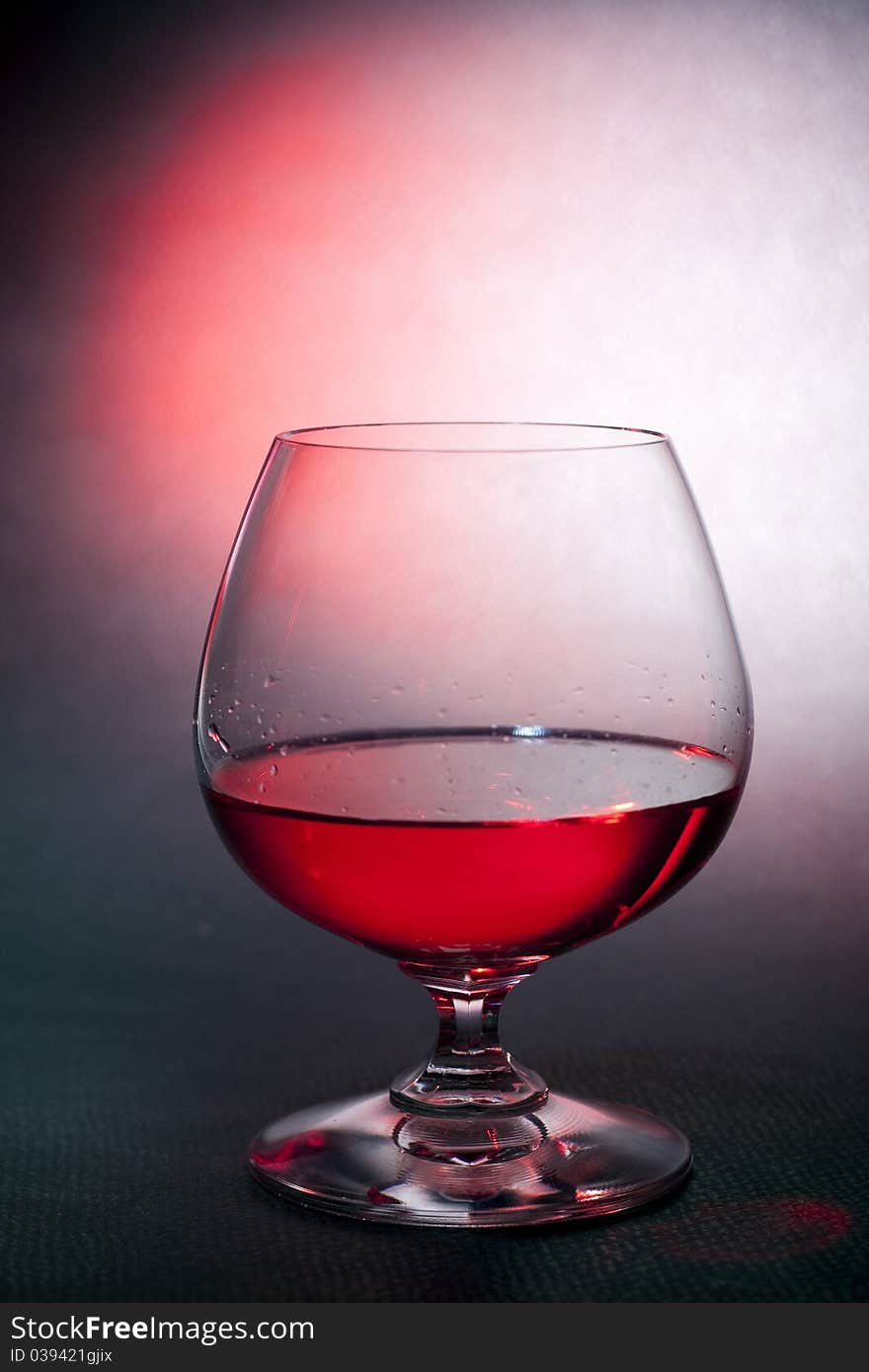 Luxury red liqueur on crystal balloon  glass, background shoot with gels. Luxury red liqueur on crystal balloon  glass, background shoot with gels