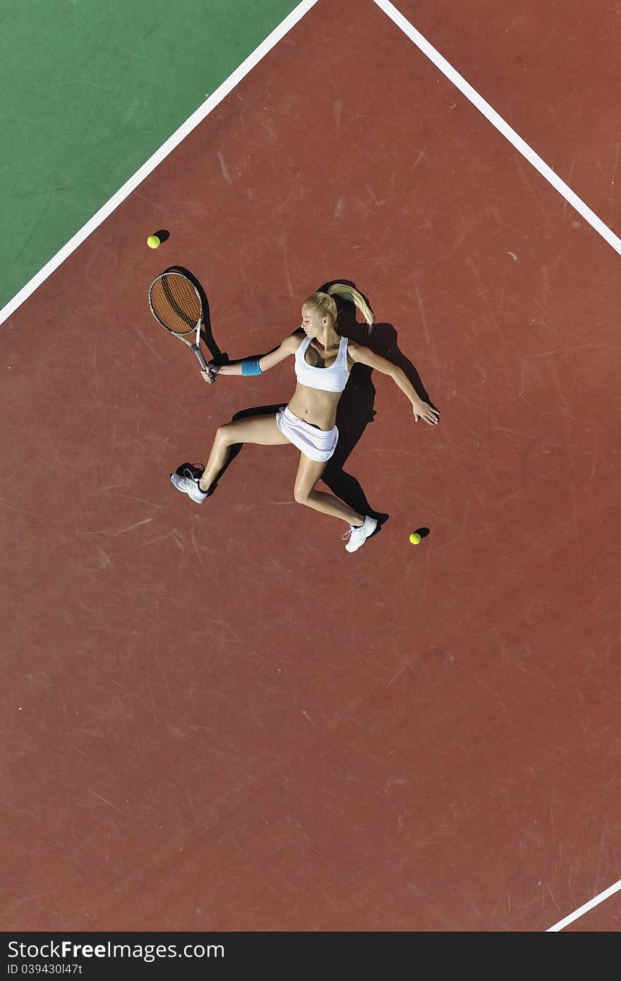 Young fit woman play tennis outdoor on orange tennis field at early morning. Young fit woman play tennis outdoor on orange tennis field at early morning