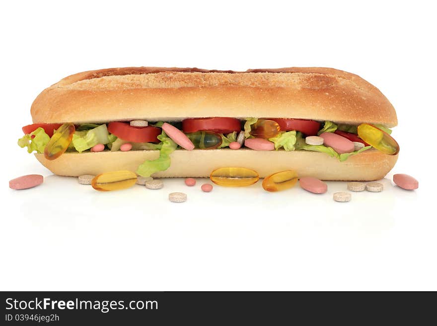 Vitamin pill selection scattered and in a cucumber, tomato and lettuce french roll, over white background. Vitamin pill selection scattered and in a cucumber, tomato and lettuce french roll, over white background.