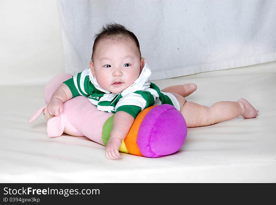 A three months baby laying on a colorful pillow and looking at camera. A three months baby laying on a colorful pillow and looking at camera