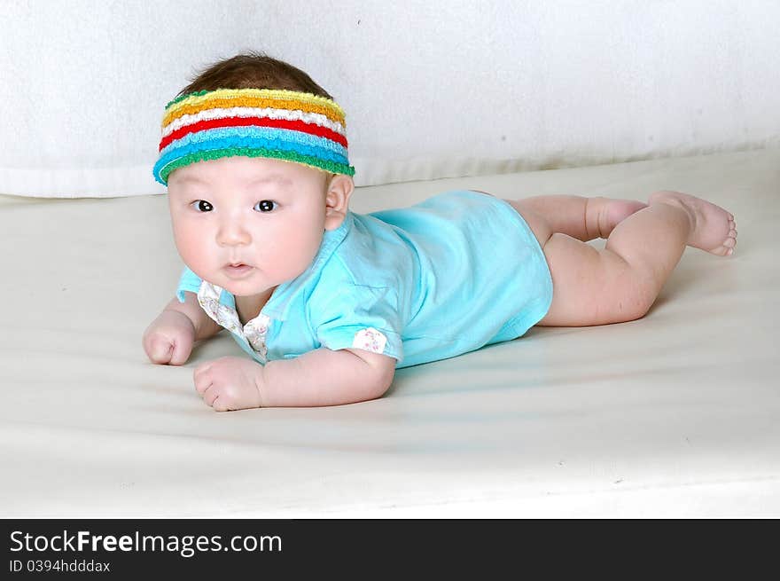 A cute baby is laying on a bed and wearing a colorful cap on his head. A cute baby is laying on a bed and wearing a colorful cap on his head