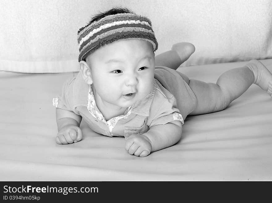 A baby is laying on a soft bed with cute expression in a black and white style. A baby is laying on a soft bed with cute expression in a black and white style