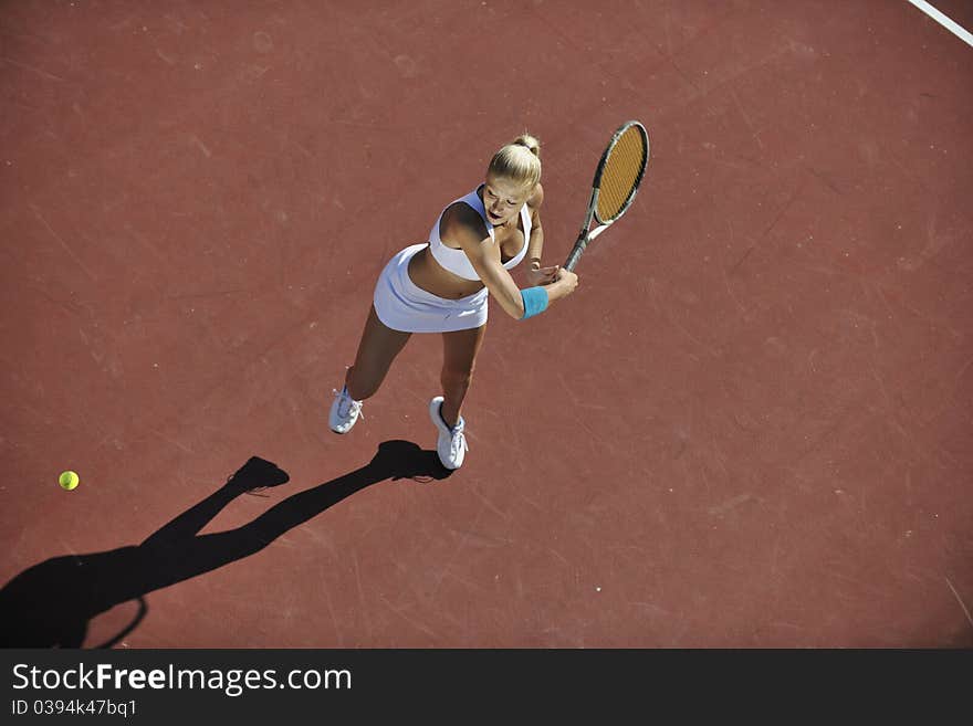 Young fit woman play tennis outdoor on orange tennis field at early morning. Young fit woman play tennis outdoor on orange tennis field at early morning