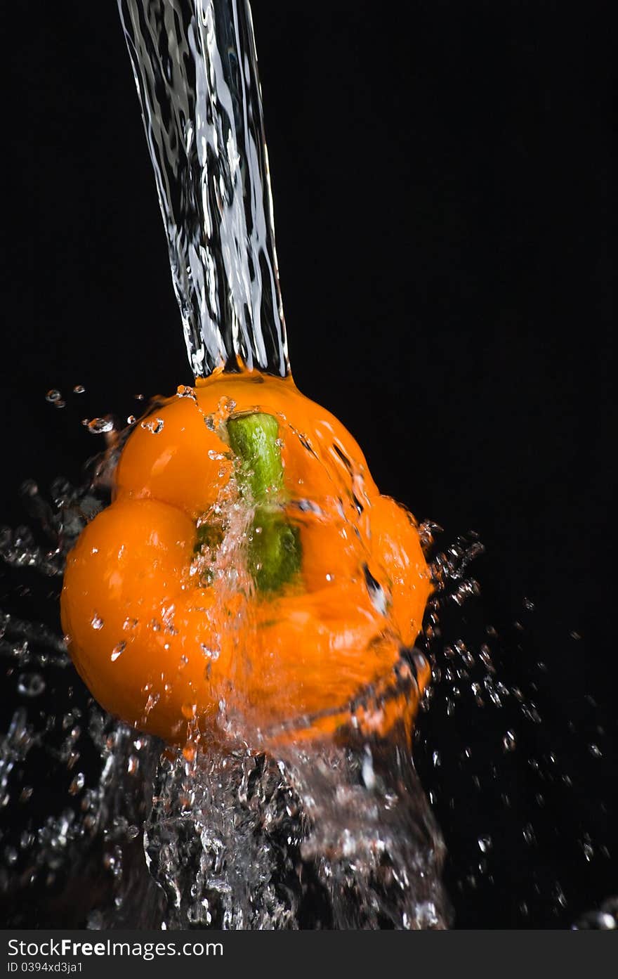 Orange bell pepper in water stream on black background. Orange bell pepper in water stream on black background