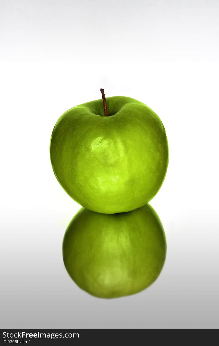 Green apple with reflection against white background