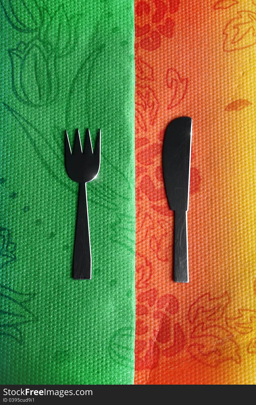 Old knife and fork on colorful tablecloth. Old knife and fork on colorful tablecloth