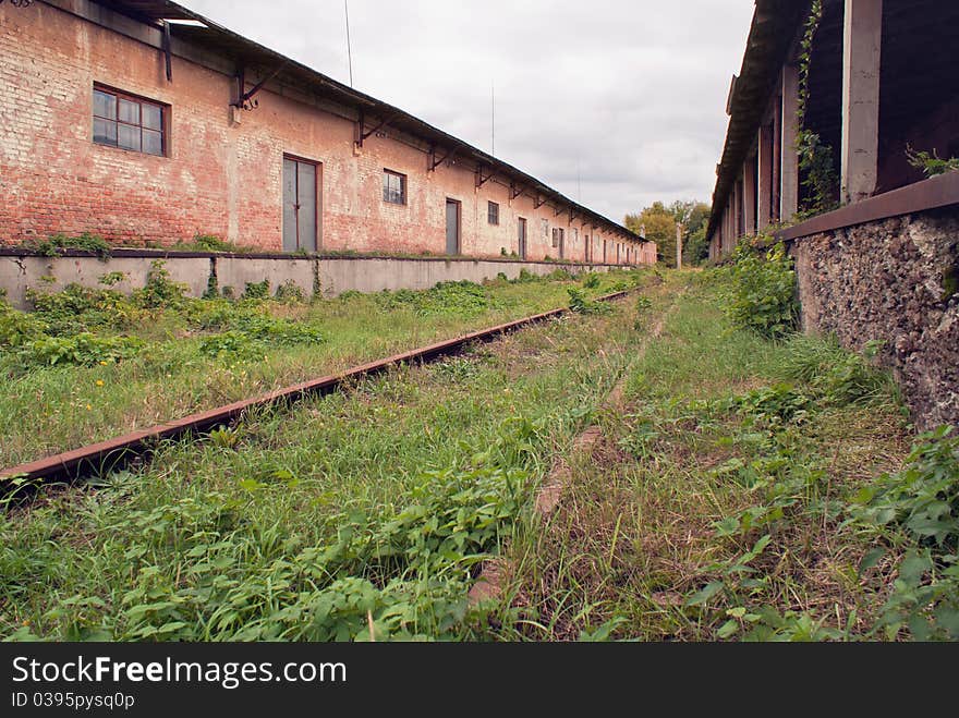 Neglected building, railway ways are copsy a grass