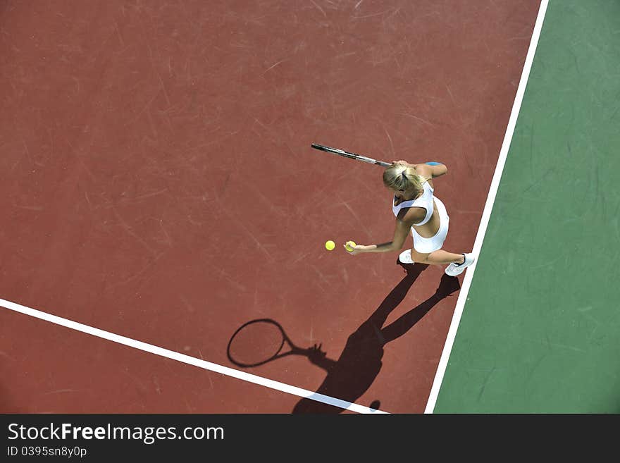 Young fit woman play tennis outdoor on orange tennis field at early morning. Young fit woman play tennis outdoor on orange tennis field at early morning