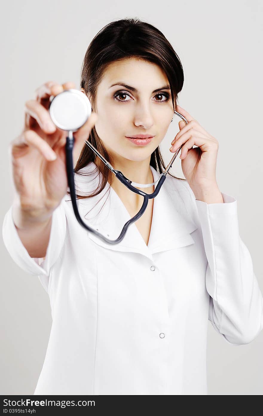 Young female doctor holding stethoscope to camera