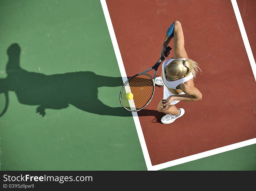 Young fit woman play tennis outdoor on orange tennis field at early morning. Young fit woman play tennis outdoor on orange tennis field at early morning