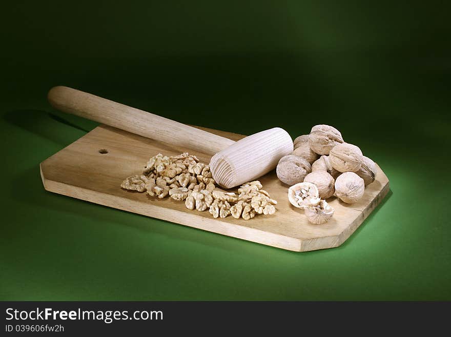 Broken nuts and hammer on a rifle-green background. Broken nuts and hammer on a rifle-green background