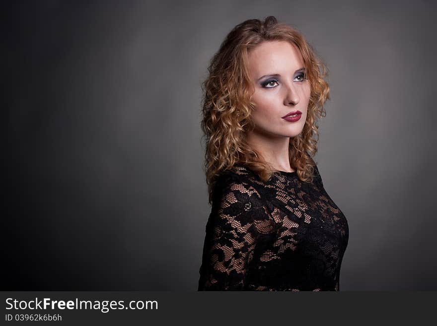 Young gorgeous model in a lace dress, a black background