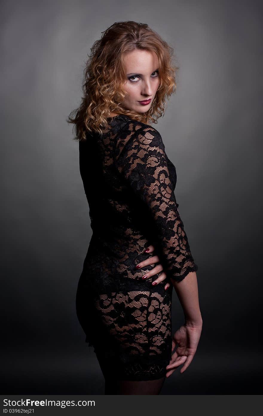 Young gorgeous model in a lace dress, a black background