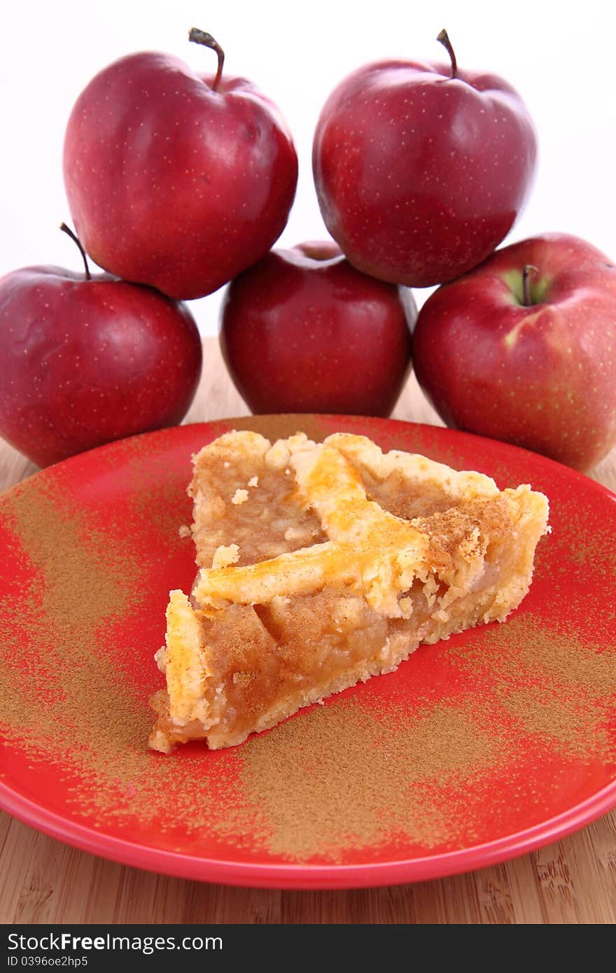 Apple Pie - a slice on a plate decorated with cinnamon and some red apples