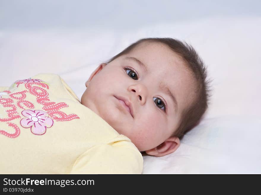 Close up of baby girl with dark hair, big dark eyes looking intensely. Close up of baby girl with dark hair, big dark eyes looking intensely.