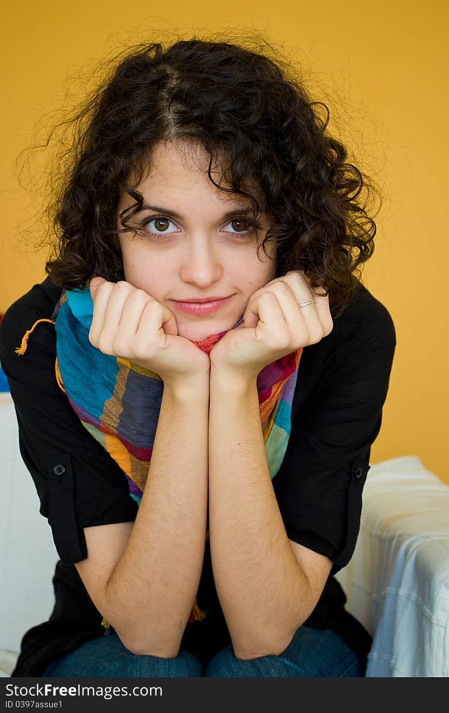 Portrait of a curly young woman smiling and siting on a sofa