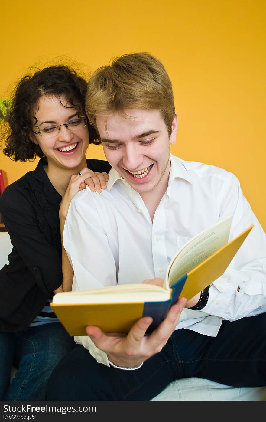 Young couple laughing while reading a book and having fun