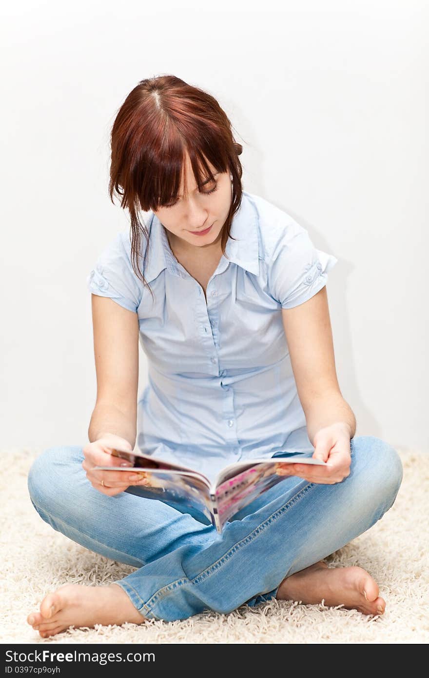 Young adult sitting on the floor with magazine