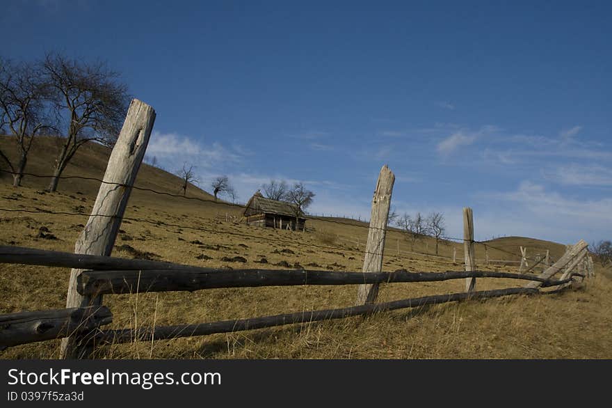 Country landscape before winter with dry grass and old house