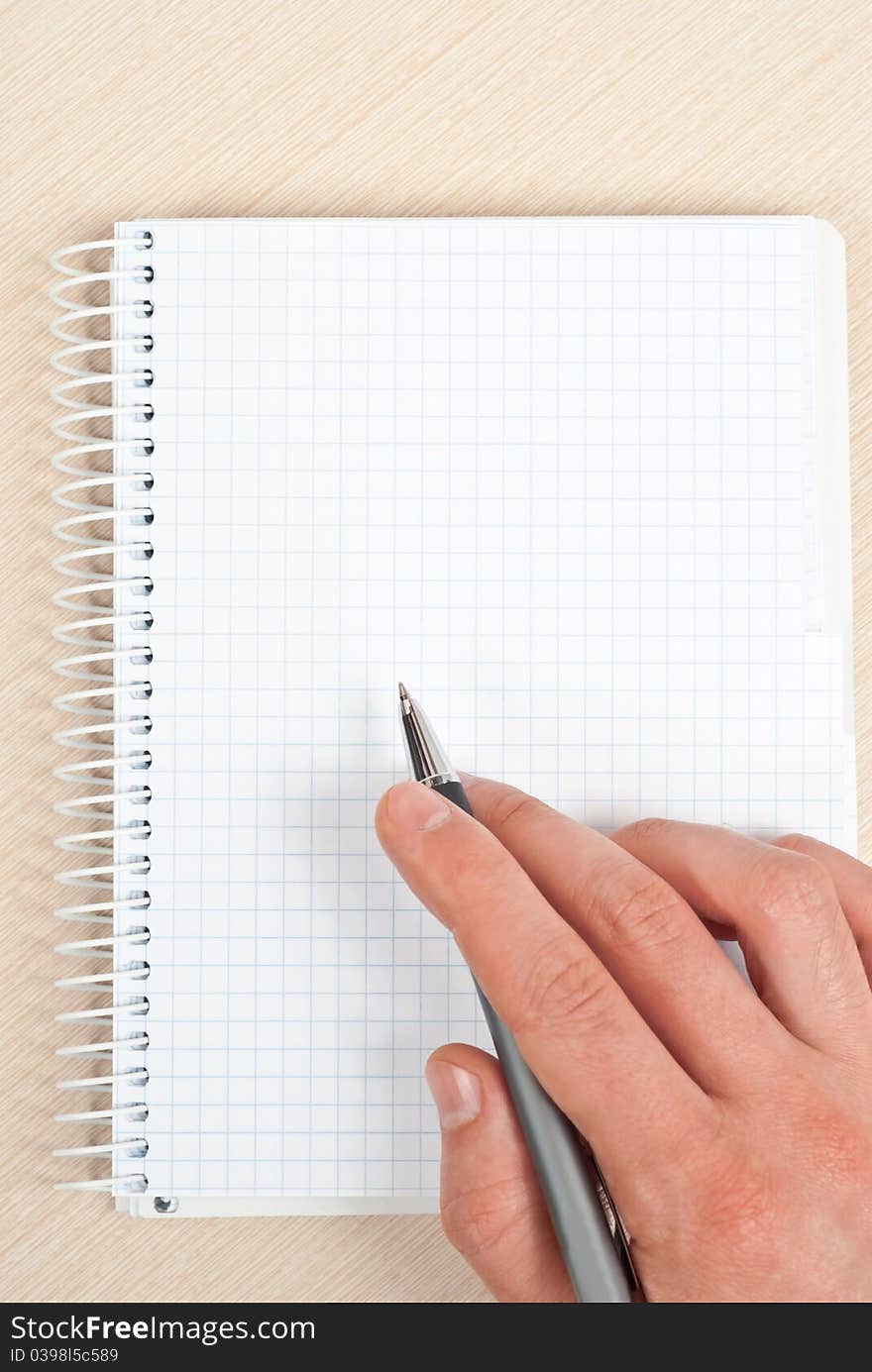 Male hand holding a pen writing notes in a notebook. Male hand holding a pen writing notes in a notebook.