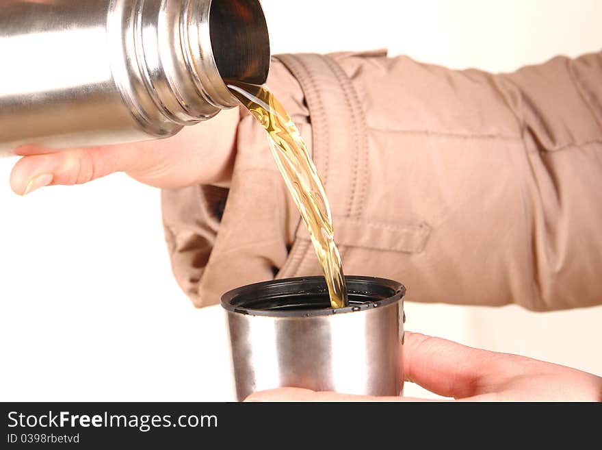 Thermos in a hand, pouring tea into a cup.