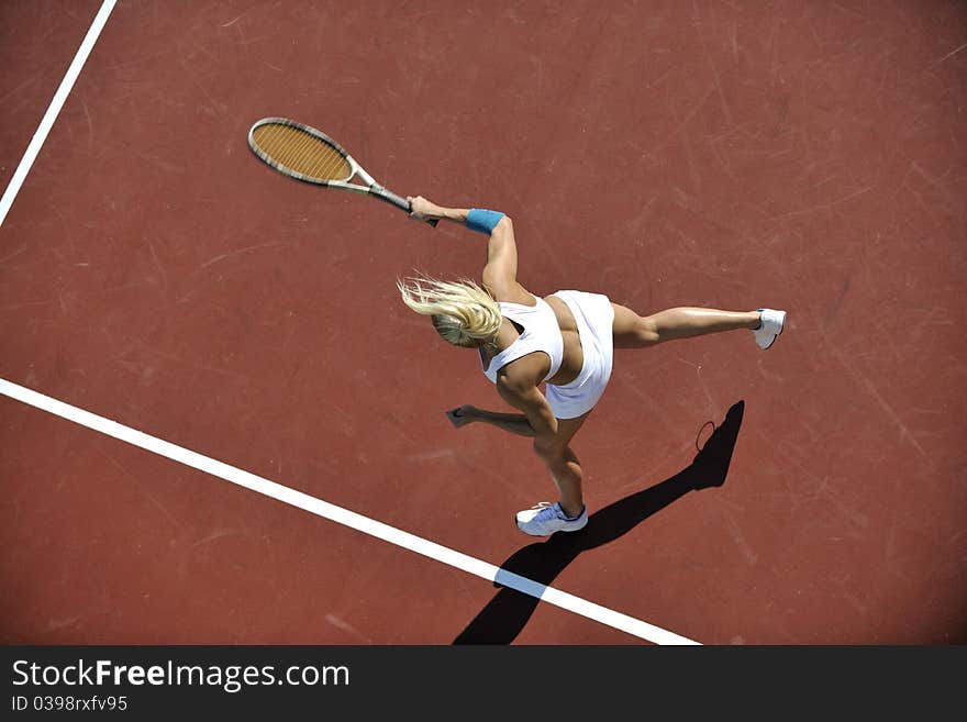 Young fit woman play tennis outdoor on orange tennis field at early morning. Young fit woman play tennis outdoor on orange tennis field at early morning