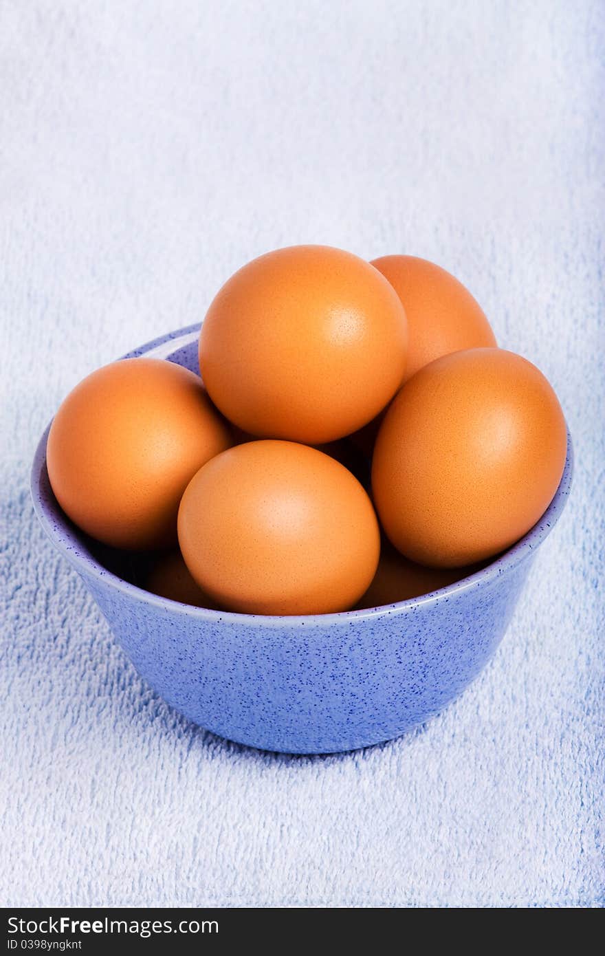 Fresh brown eggs in blue bowl