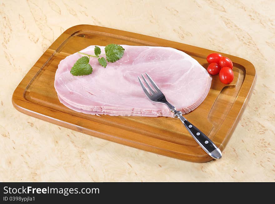 Cooked ham on a wooden board in the kitchen.