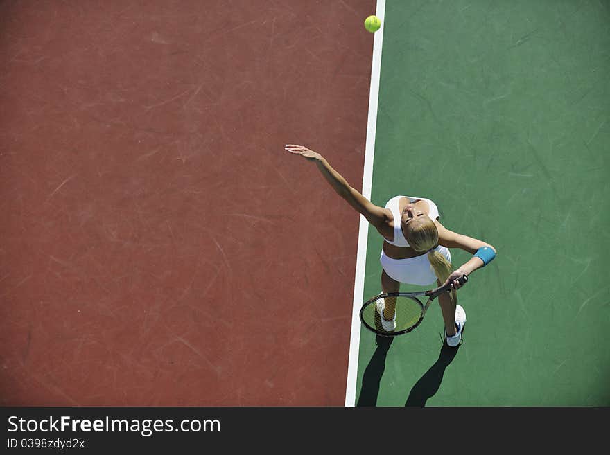 Young fit woman play tennis outdoor on orange tennis field at early morning. Young fit woman play tennis outdoor on orange tennis field at early morning