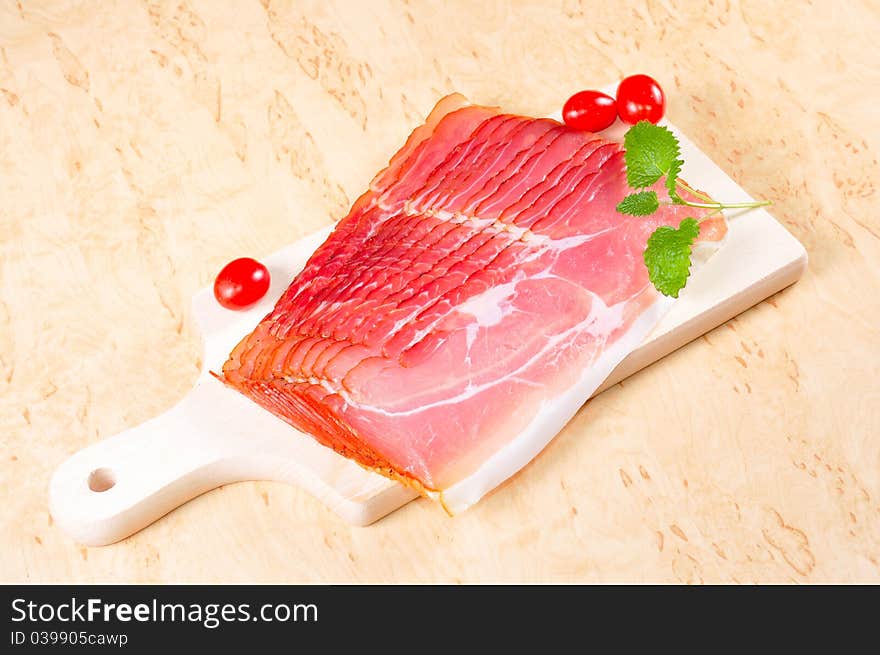 Raw ham on a wooden board in the kitchen.