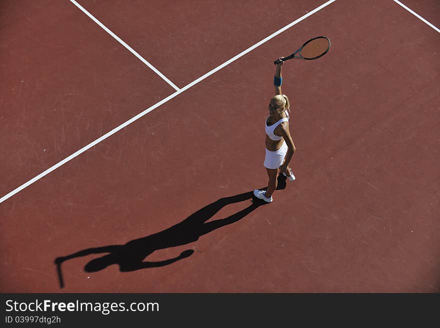 Young fit woman play tennis outdoor on orange tennis field at early morning. Young fit woman play tennis outdoor on orange tennis field at early morning