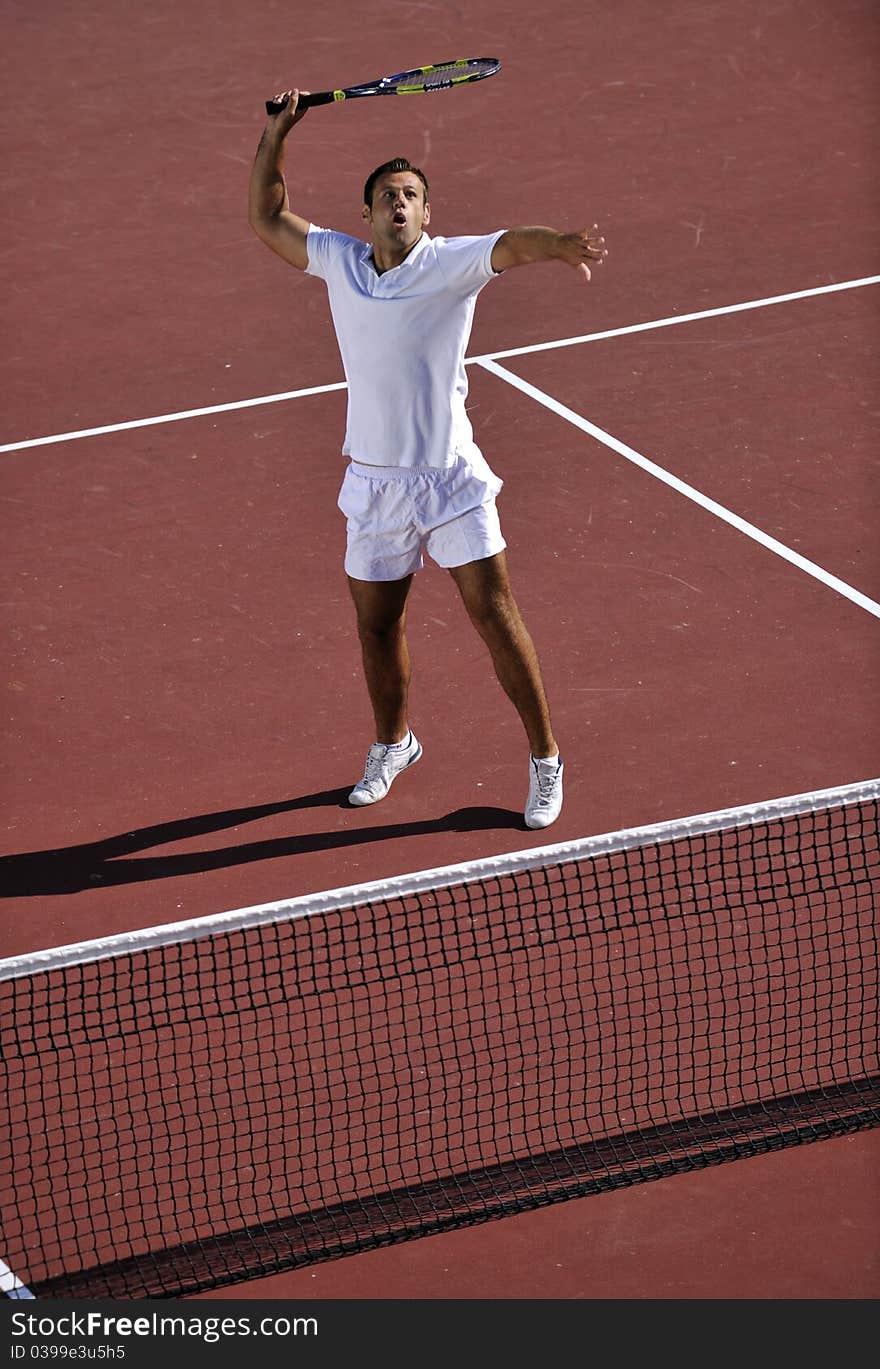 Young man play tennis outdoor on orange tennis field at early morning