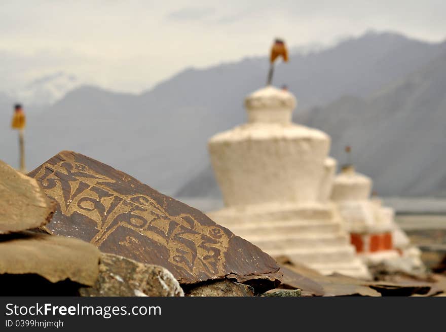 Mani stone containing the Buddhist prayer Om Mani Padme Hum and white chortens in Ladakh, India